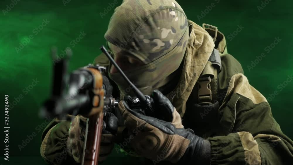 soldier-saboteur with a Kalashnikov rifle talking on the radio on a dark background soldier-saboteur with a Kalashnikov rifle talking on the radio on a dark background