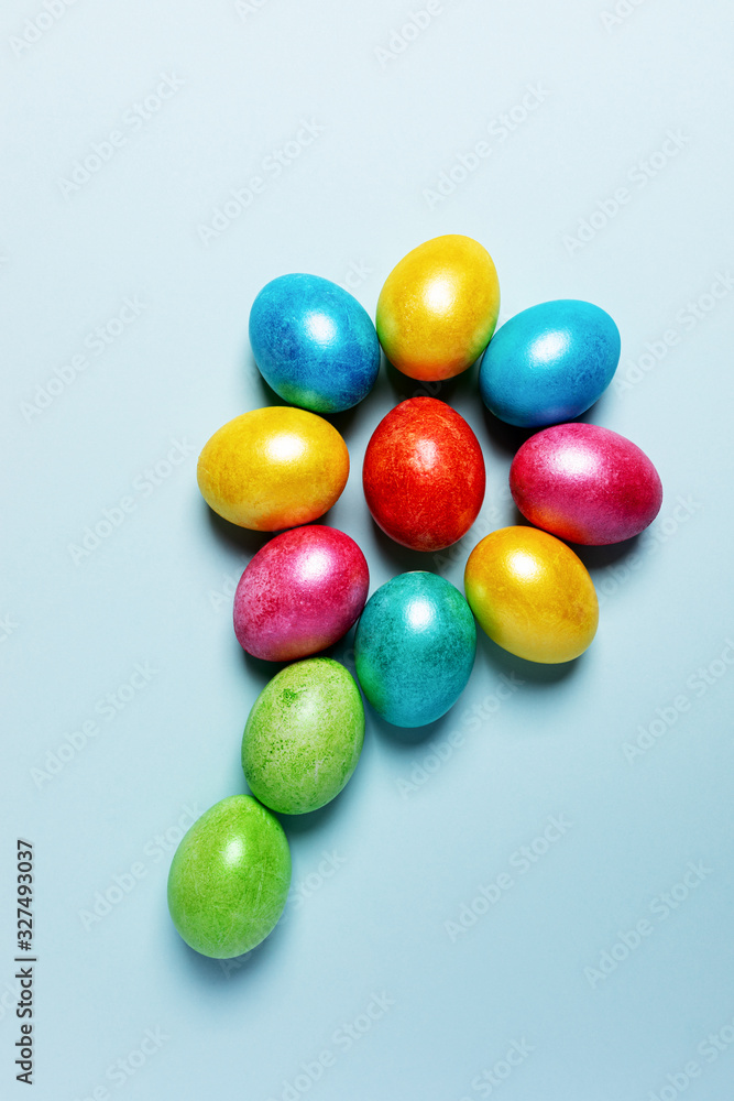 Easter festive composition. Colored glossy Easter eggs laid out in form of flower on light blue pastel background. Easter festive composition. Colored glossy Easter eggs laid out in form of flower on light blue pastel background.