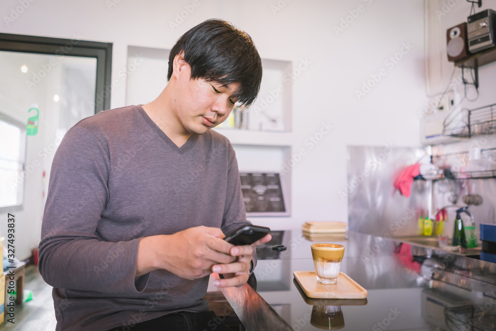 Attractive Asian man using smartphone to take coffee photos at the table in coffee shop. Film tone effected. Attractive Asian man using smartphone to take coffee photos at the table in coffee shop. Film tone effected.