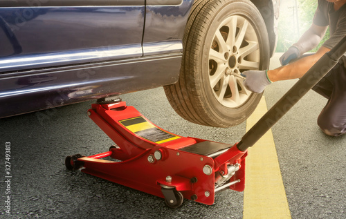 Red hydraulic  floor jack ,Asia man with a blue car that broke down on the road.Changing tire on broken car on road ,clipping path photo