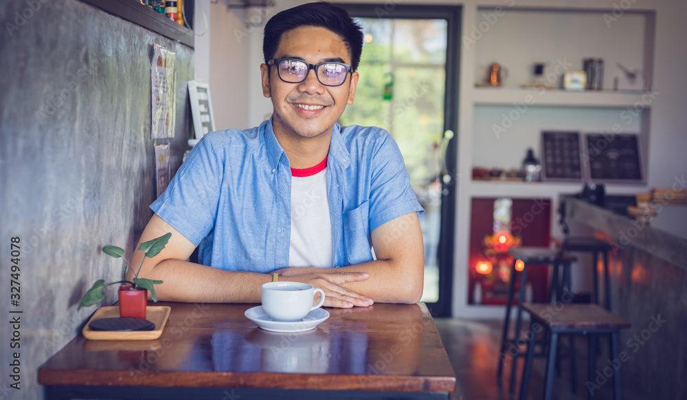 Attractive Asian man with coffee at the table in coffee shop. Film tone effected. Attractive Asian man with coffee at the table in coffee shop. Film tone effected.
