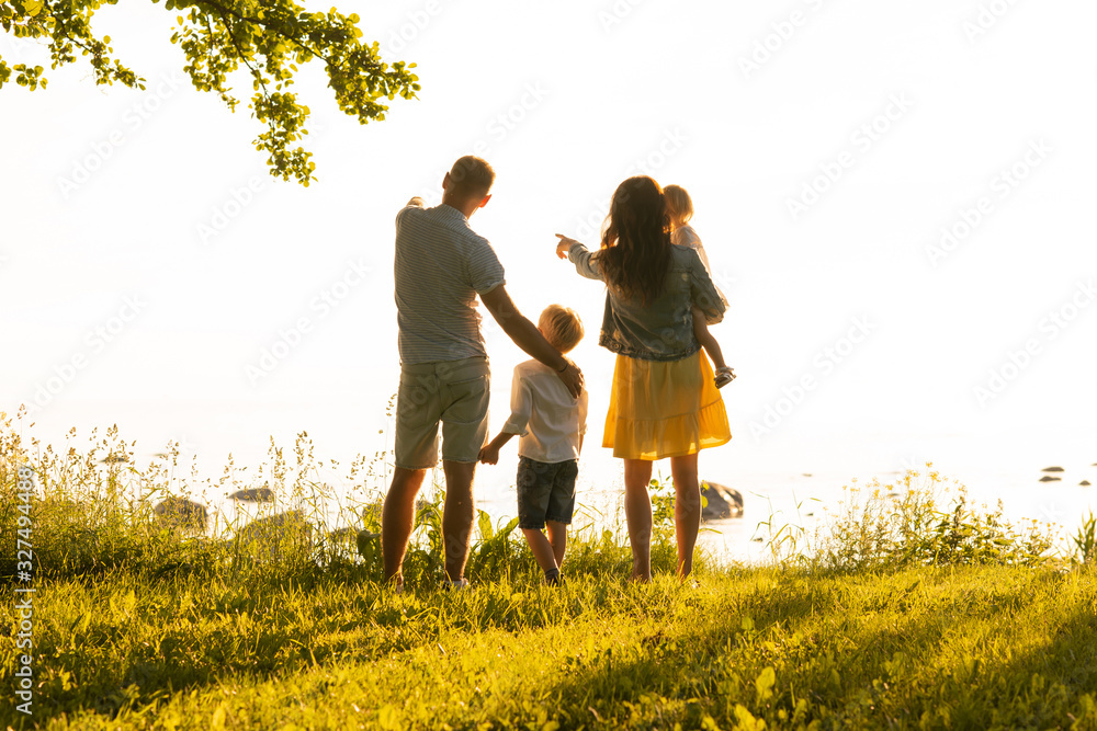 Happy loving family walking outdoor in the light of sunset. Father, mother, son and daughter. Happy loving family walking outdoor in the light of sunset. Father, mother, son and daughter.