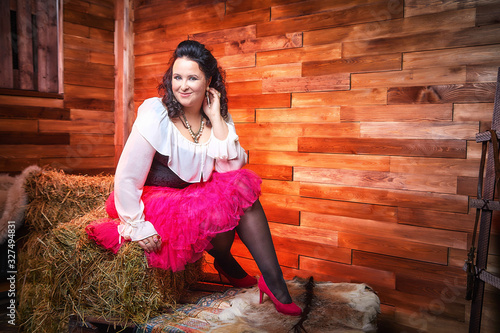 Portrait of fat plump fun charming cute woman with black curly hair in the room with hay and straw photo