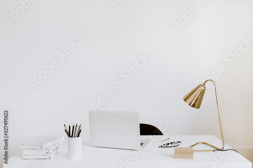 Office with laptop, lamp, notebooks. White working study cabinet. Outsourcing freelancer, blogger, boss workspace.