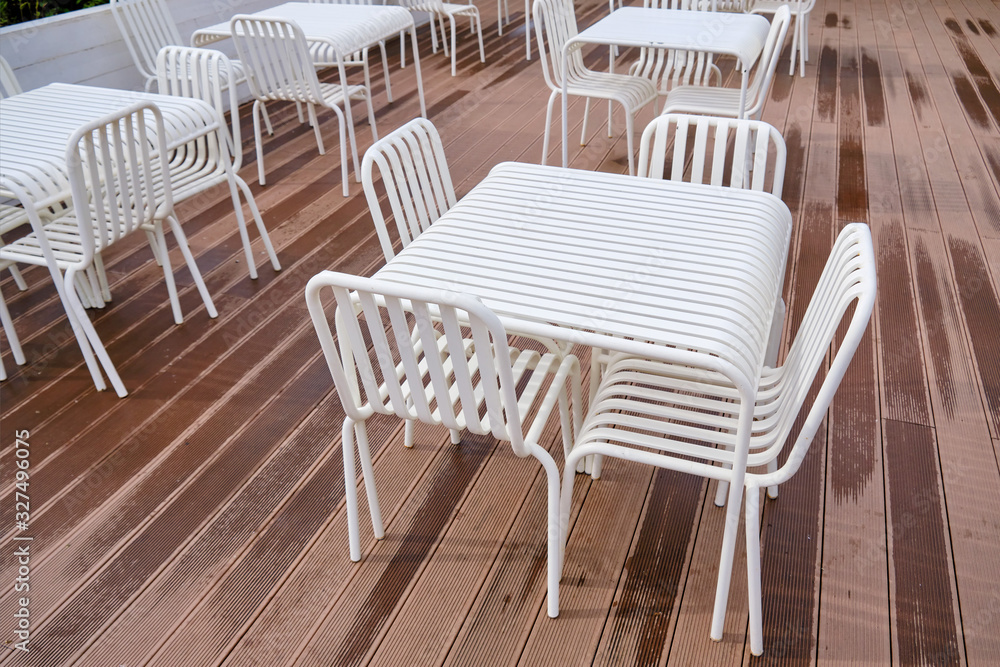 Empty white tables and chairs, furniture in an outdoor summer cafe