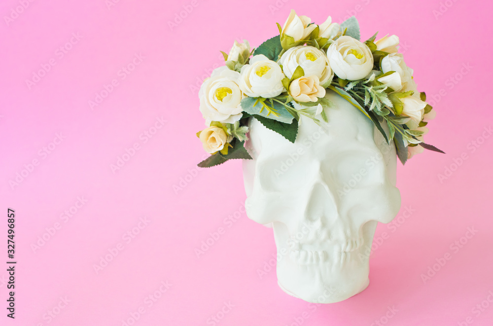 Obraz premium Plaster skull with white flower crown on pink background