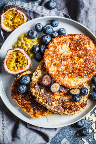 Oatmeal pancakes with honey, fruits and berries, blue background, top view. Healthy vegan food concept.