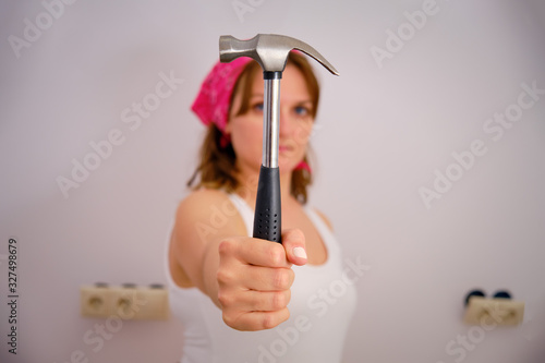 Woman holds big hammer on outstretched arm photo