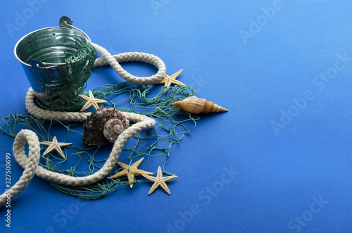 Closeup of bucket, amrine rope and net, seashell on the blue background.Empty space for design photo