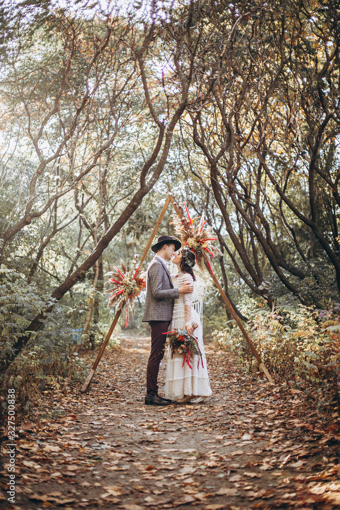 Bride and Stylish Groom. Happy wedding couple at a wedding ceremony outdoors in the park during sunset. Atmospheric glow of the sun and beautiful lovers - Perfect Wedding background Bride and Stylish Groom. Happy wedding couple at a wedding ceremony outdoors in the park during sunset. Atmospheric glow of the sun and beautiful lovers - Perfect Wedding background