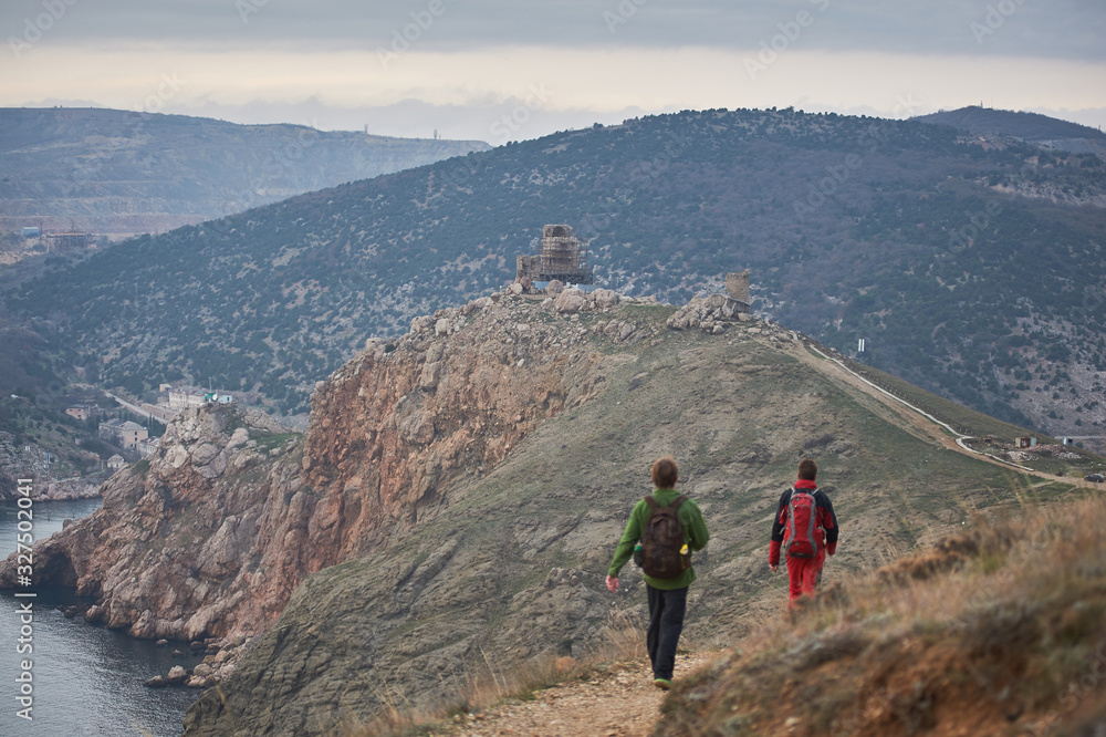 Fototapeta premium Trekkers are finishing their mountain rout and getting closer to a rocky scenic suburbs of the city.