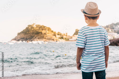 Little kid with hat looking the sea on the beach