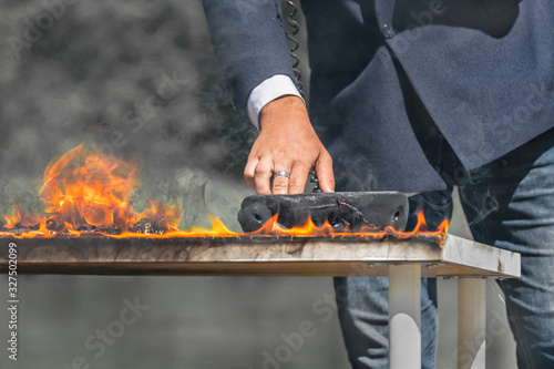 man in a business suit on a background of nature near a burning office desk is calling on a landline phone