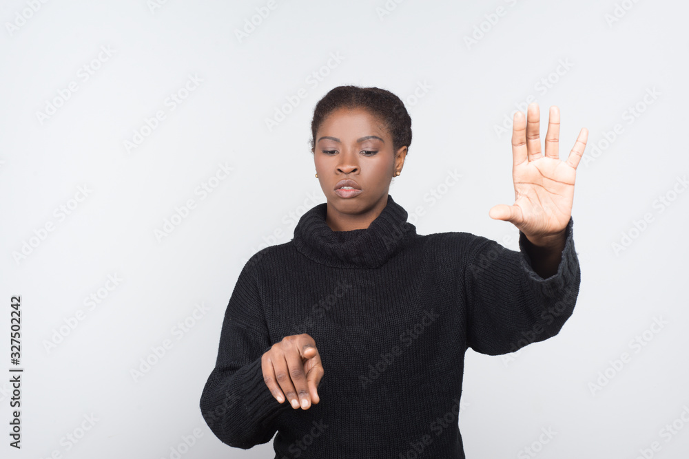 Front view of serious woman touching virtual screen. Attractive young lady pressing something on imaginary screen. Virtual screen concept Front view of serious woman touching virtual screen. Attractive young lady pressing something on imaginary screen. Virtual screen concept