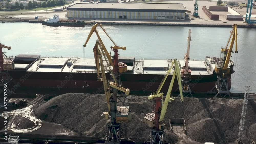 VENTSPILS, LATVIA - JULY, 2019: Aerial view of port crane that loads cargo into dry cargo ship and railway carriage. VENTSPILS, LATVIA - JULY, 2019: Aerial view of port crane that loads cargo into dry cargo ship and railway carriage.