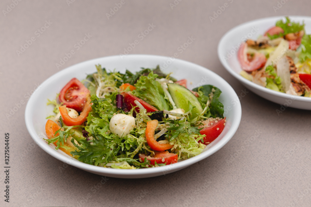 white deep plates with fresh salad ingredients mixed with sauce placed on an attractive background. A place for a menu, banner or advertisement white deep plates with fresh salad ingredients mixed with sauce placed on an attractive background. A place for a menu, banner or advertisement