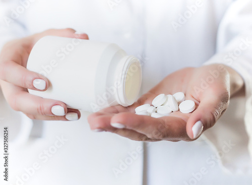 Young woman pours out medicine  capsule or pill into her hand. Healthcare and medical concept.