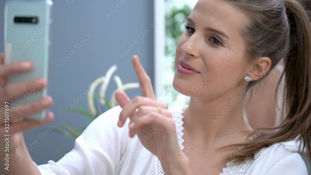 Happy adult woman using smartphone in bathroom in the morning Happy adult woman using smartphone in bathroom in the morning