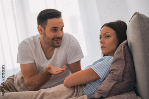 Young couple is taking in bed. Woman is offended and angry.