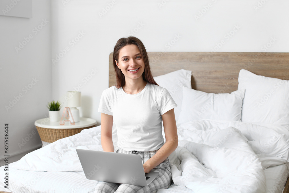 Morning of beautiful young woman with laptop in bedroom Morning of beautiful young woman with laptop in bedroom