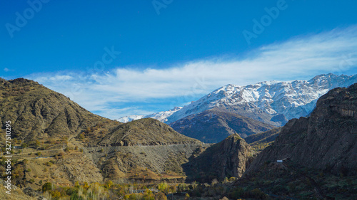 a view of mountains covered with snow in the fall season in the north of Iraq Kurdistan Region with green landscape and trees in the foreground