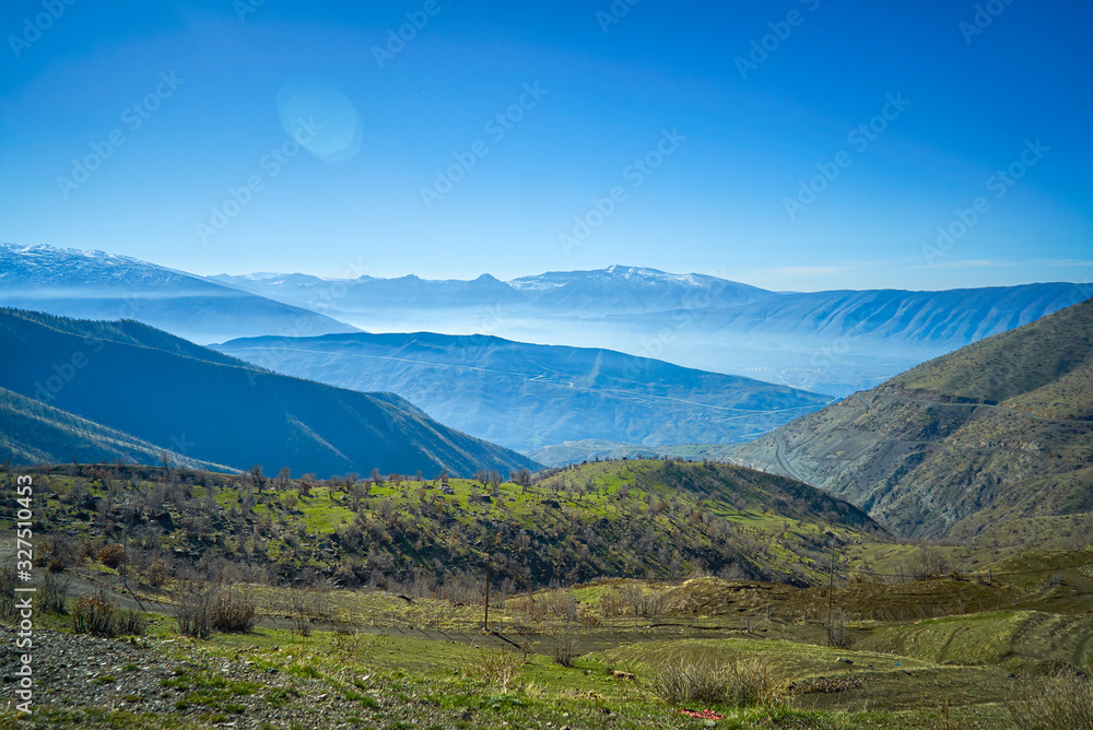 a view of mountains covered with snow in the fall season in  the north of Iraq Kurdistan Region with green landscape and trees in the foreground