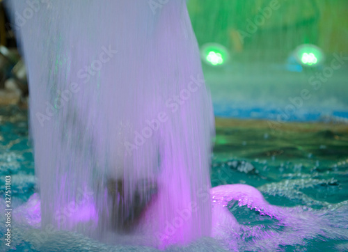 Blurred water background. Backlit water jet in the fountain. photo