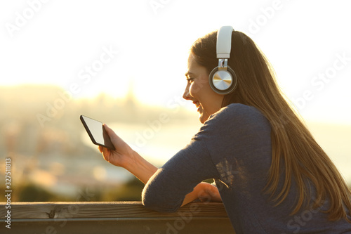 Happy woman with headphones watching videos on phone photo