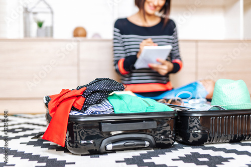 Beautiful young woman packing her stuff into a big suitcase. Traveling preparation concept.