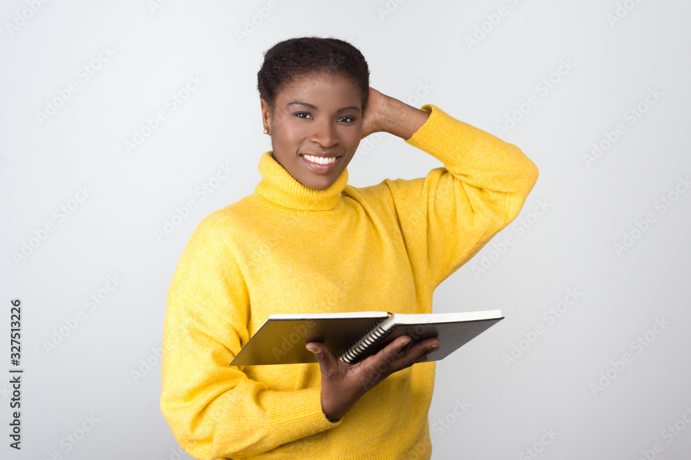 Smiling African American student with notepad. Cheerful young lady with open notebook looking at camera. Education, tuition concept Smiling African American student with notepad. Cheerful young lady with open notebook looking at camera. Education, tuition concept