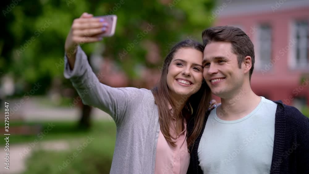 Happy couple spending time outdoors and using smartphone Happy couple spending time outdoors and using smartphone