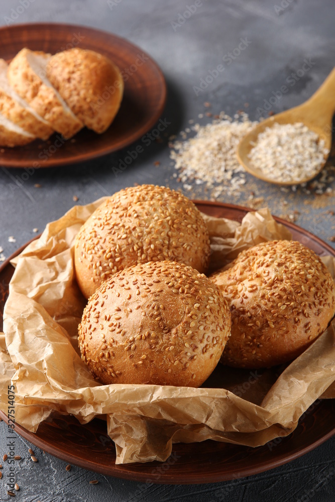 Bakery. Bread with sesame seeds on parchment on the brown plate. Bread slices lie near to the plate. On a light grey background. Background image, copy space