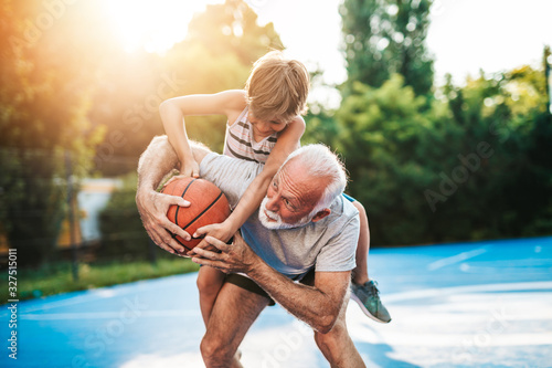 Fototapeta Naklejka Na Ścianę i Meble -  Grandfather and his grandson playing basketball.