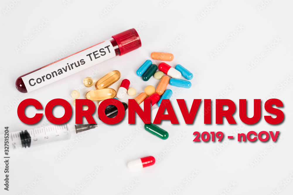 Obraz premium colorful pills near sample with coronavirus test, syringe and coronavirus 2019-ncov lettering on white