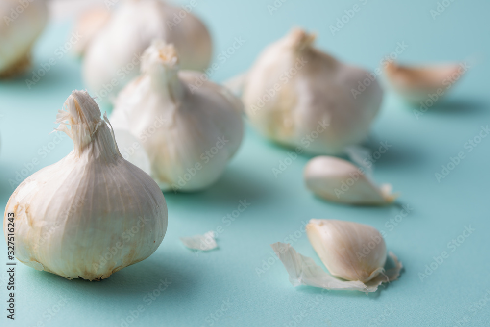 Obraz premium A lot of garlic on a light blue background. Close up, horizontal photo