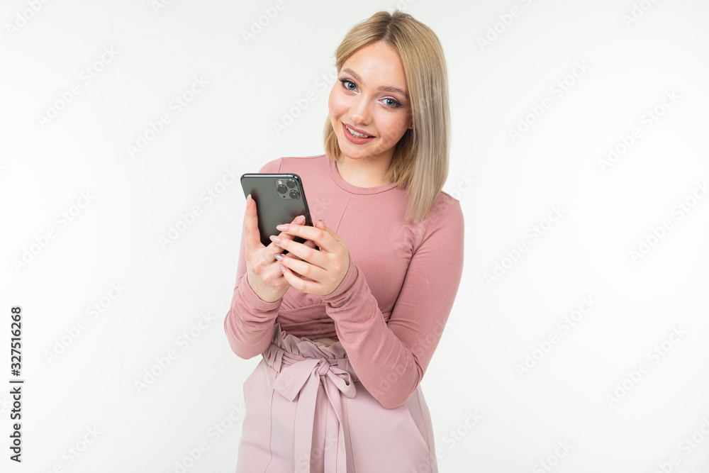 smiling girl in pink clothes with a smartphone in hands on a white background smiling girl in pink clothes with a smartphone in hands on a white background