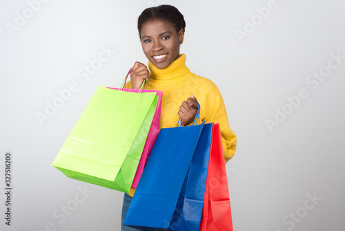 Beautiful cheerful woman holding colorful shopping bags. Attractive smiling young lady with paper bags looking at camera. Shopping concept © Mangostar