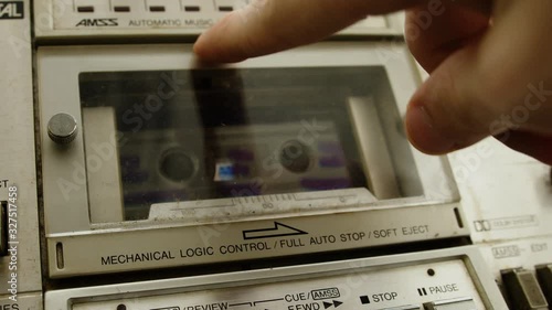 The old cassette player inserts a cassette into the boombox and presses the play button. Retro cassette player concept. photo