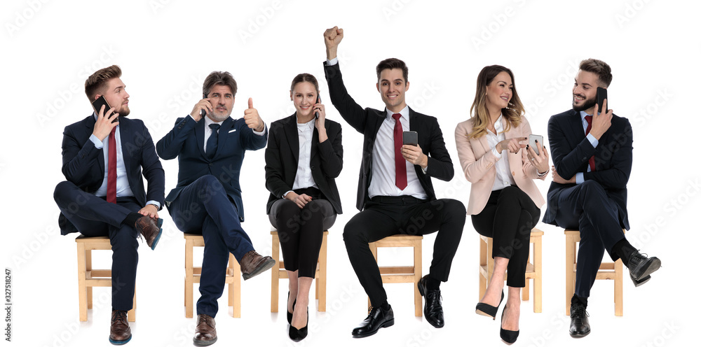 Team of 6 businessmen celebrating and holding their phones Team of 6 businessmen celebrating and holding their phones