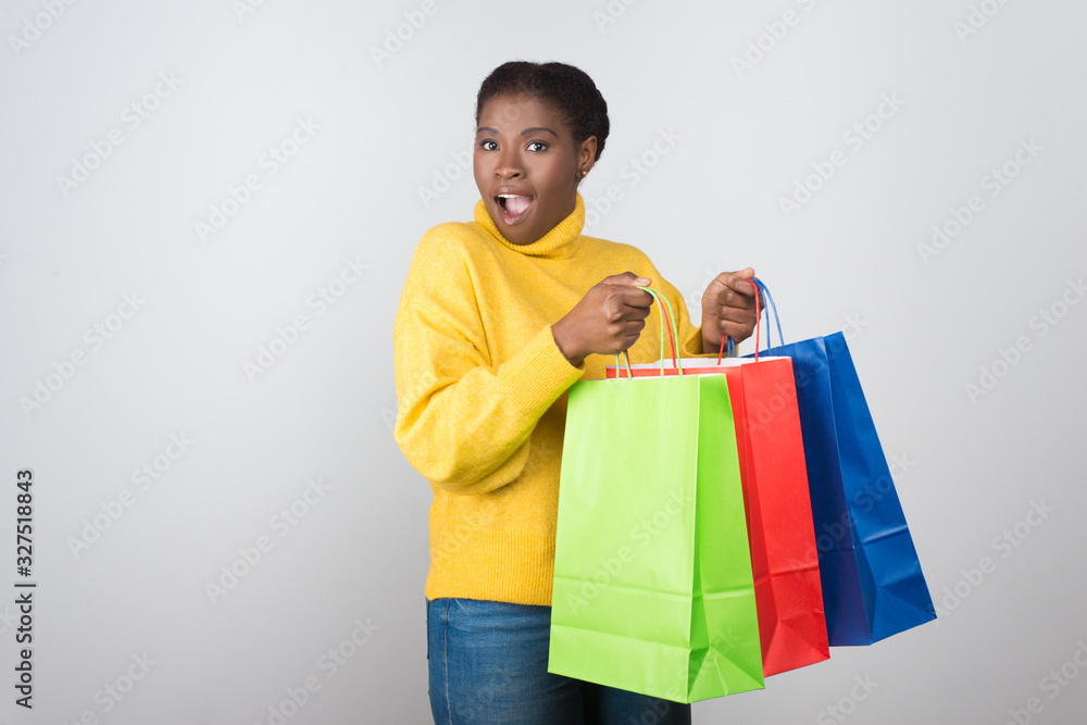 Front view of surprised beautiful woman with shopping bags. Attractive amazed young lady holding colorful paper bags. Shopping concept Front view of surprised beautiful woman with shopping bags. Attractive amazed young lady holding colorful paper bags. Shopping concept