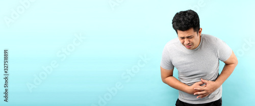  handsome of asian man Sick has stomachache isolated on blue background in studio With copy space.