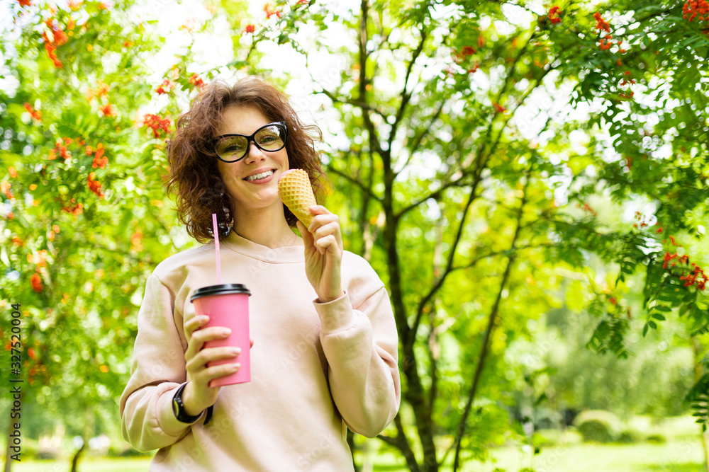 Pretty young caucasian woman go for a walk at park with coffe and ice-cream Pretty young caucasian woman go for a walk at park with coffe and ice-cream