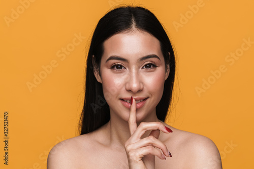 Beauty portrait of young brunette half-naked woman keeping finger at lips