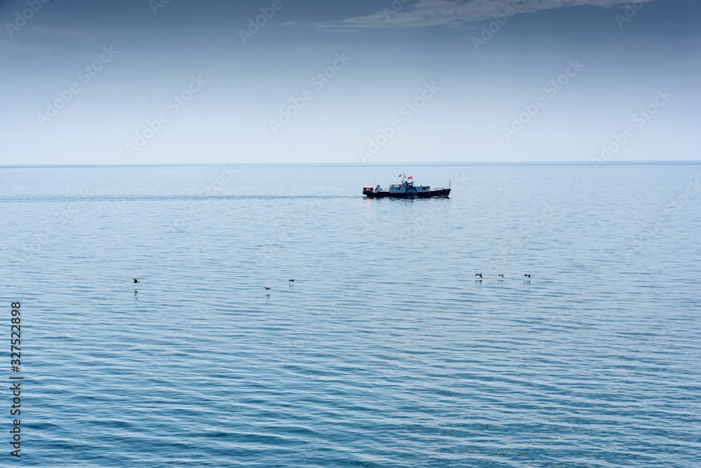 Small white ship at the Baikal lake in siberia with flying gulls, Russia Small white ship at the Baikal lake in siberia with flying gulls, Russia