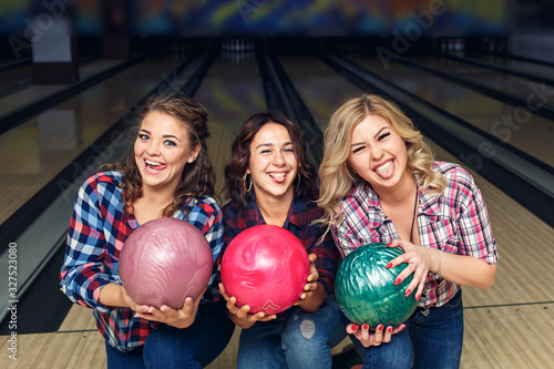 three happy girls posing with bowling balls in club