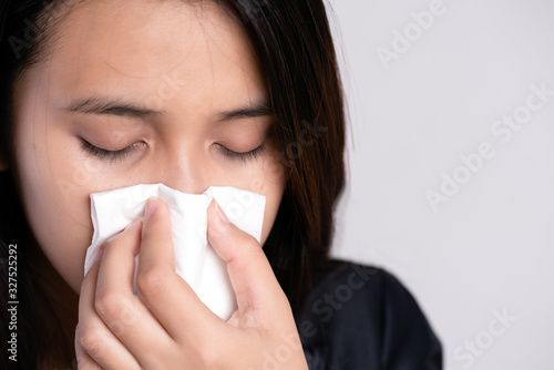Close up young asian woman got sick, flu and nose allergy sneezing in a tissue. Healthcare and Coronavirus concept.