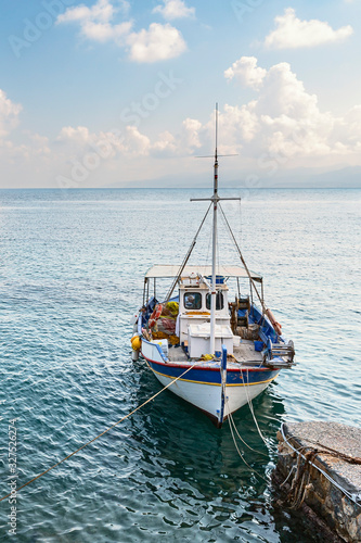 view of a small fishing boat parked at a concrete pier against the background of and blue sky