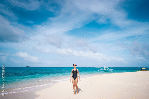Vacation on the seashore. Young woman walking on the beautiful tropical white sand beach.