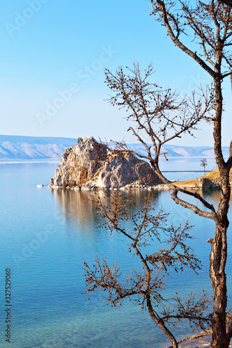 Baikal Lake on a sunny May day. A view of the natural landmark - Shamanka Rock from the coast of Olkhon Island. Beautiful spring landscape. Nature background