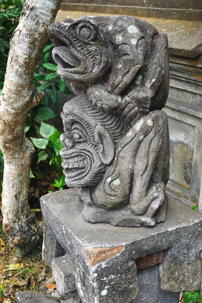 Ancient carved stone totem sculpture outside a temple in Bali Indonesia
